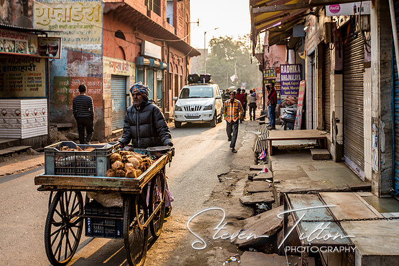 Local merchant pushes his cart down the street.