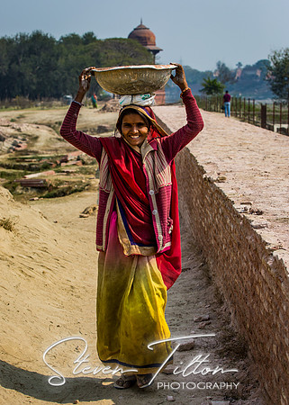 A woman carries a basket along the Yamuna River.